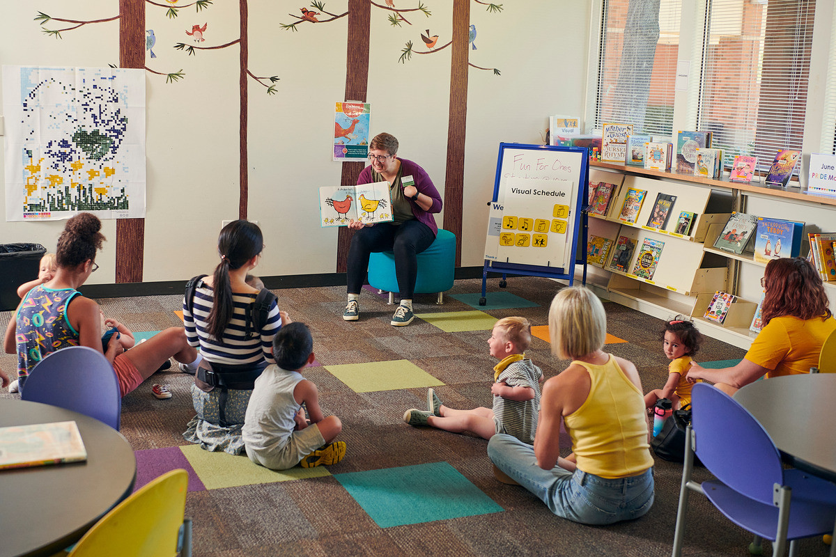 Children and adults seated on the floor, participating in a storytime reading