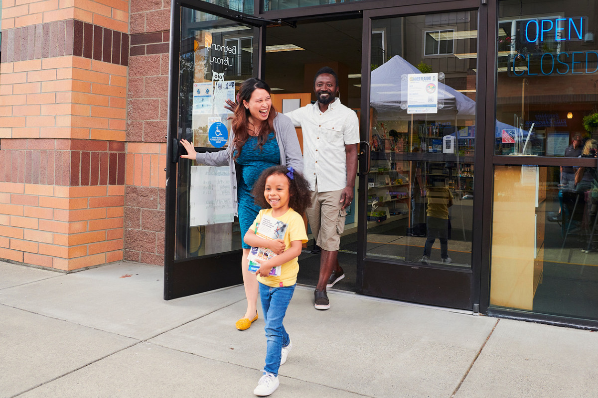 Man, woman and child walk out the door of the Bethany Library