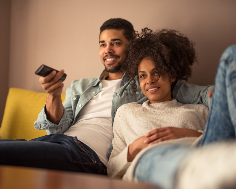 Pareja acurrucada en el sofá viendo la televisión