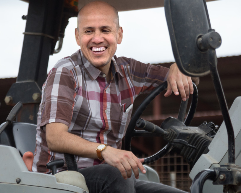 Man wearing a plaid shirt sitting behind the wheel of a tractor