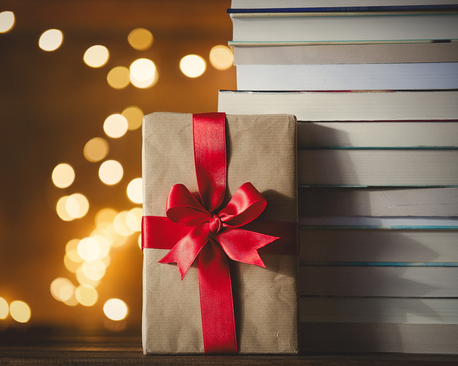 wrapped present with red bow next to a stack of books