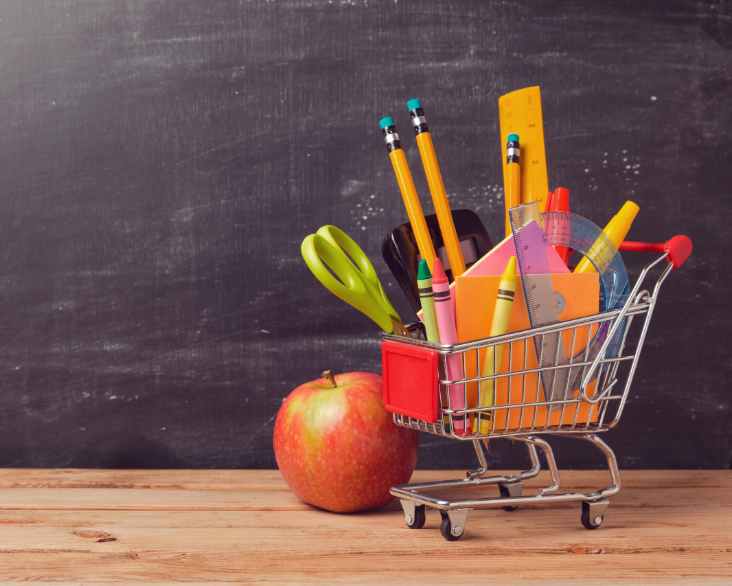 apple next to shopping cart full of school supplies