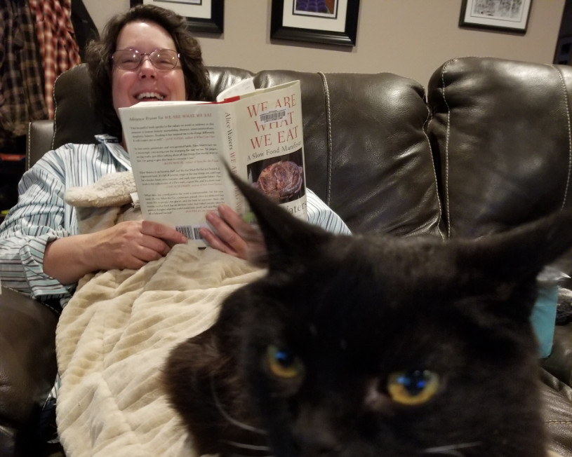 Woman reading under a black cat