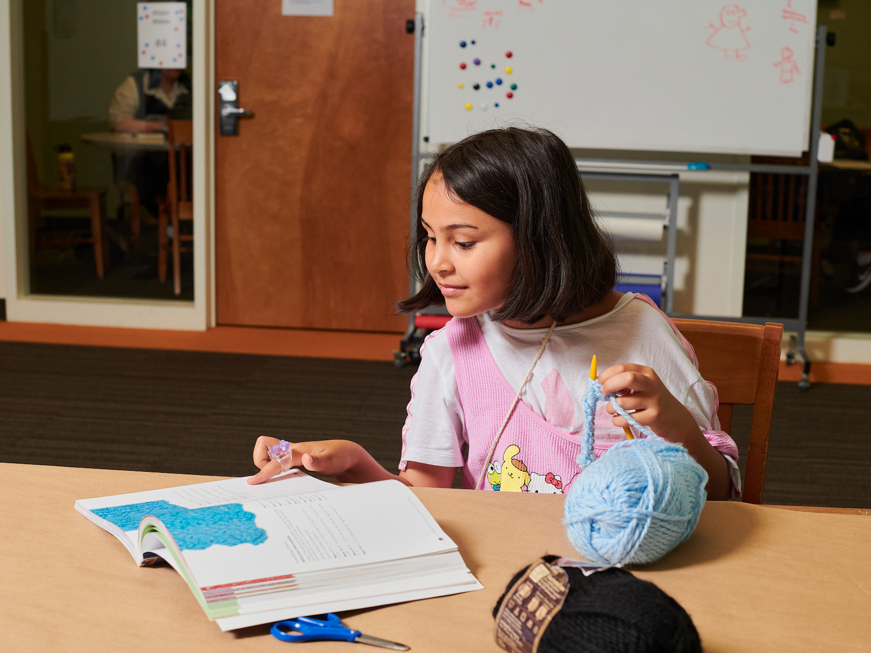 Girl knitting with yarn at the library