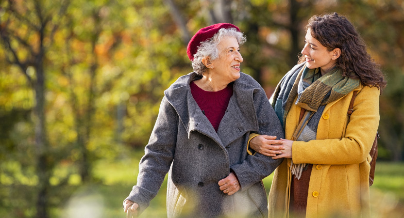 Older woman and younger woman walking arm in arm outside on a fall day