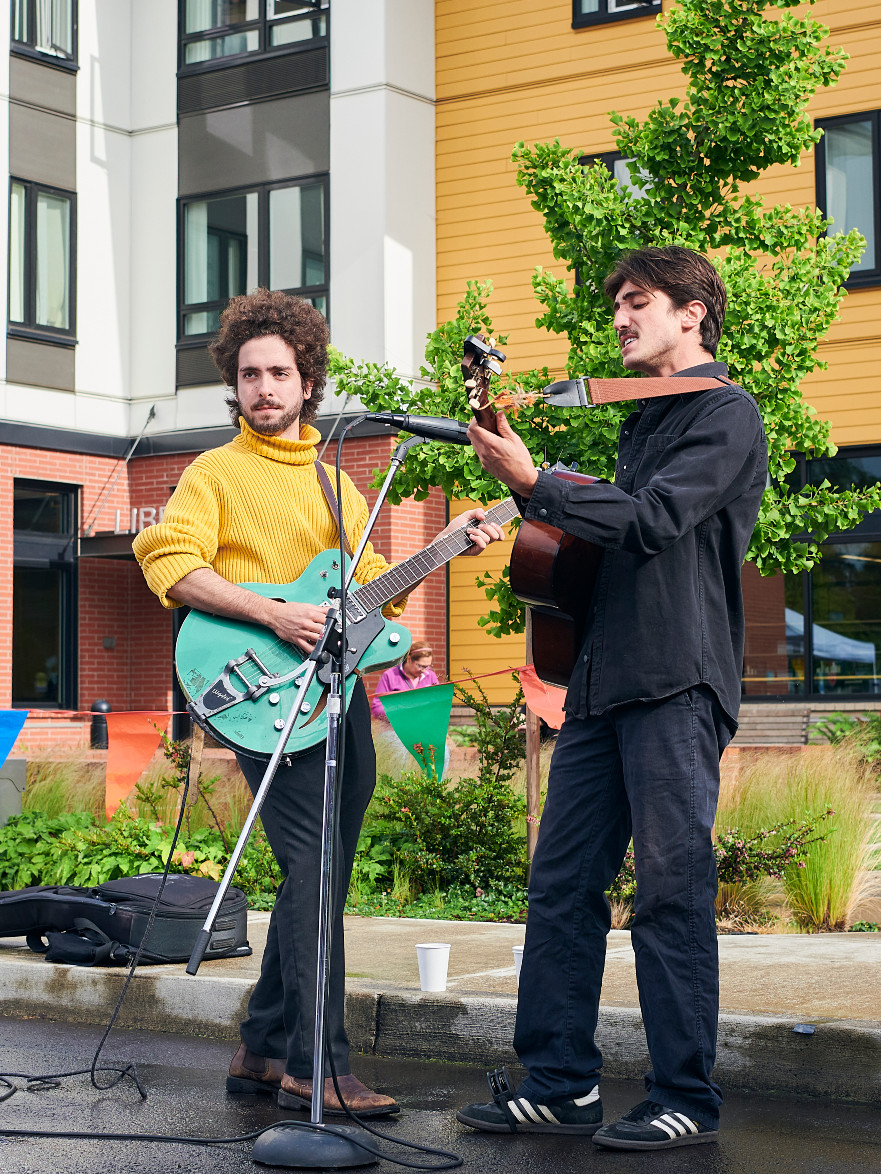 dos músicos tocando la guitarra fuera de la biblioteca