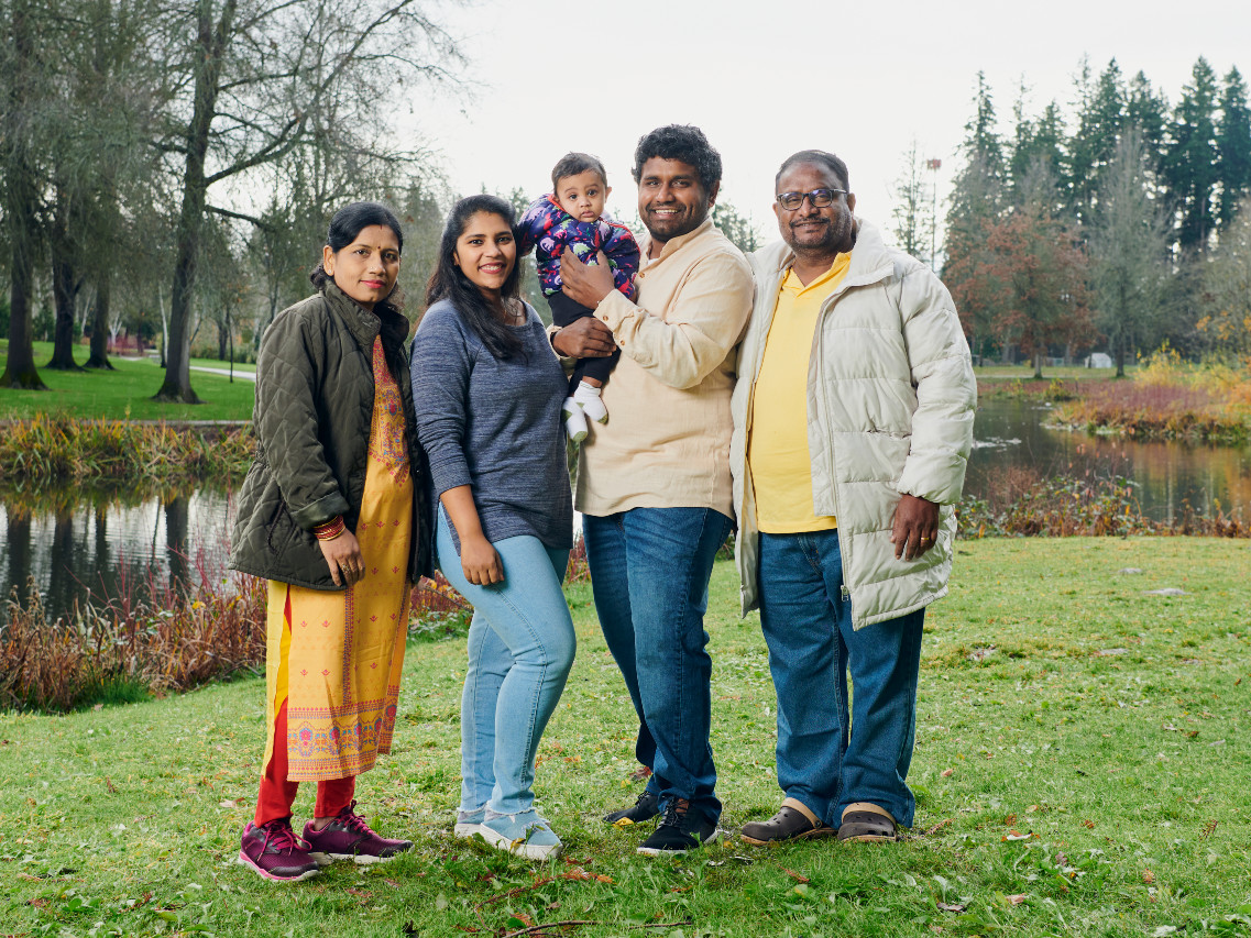 multi-generational family standing outside in front of a pond and trees