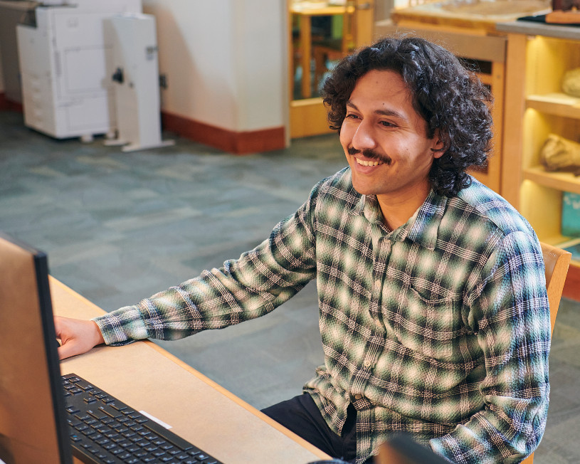 Hombre sonriente frente a la computadora en la biblioteca