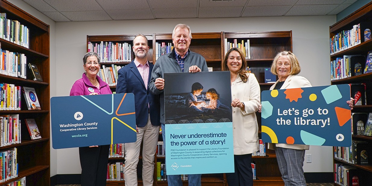 Kathryn Harrington, Kregg Arntson, Paul Sander, Angelica Espinosa, and Pam Treece proudly display a keepsake poster gifted from the PGE Foundation alongside oversized WCCLS library cards at West Slope Library.