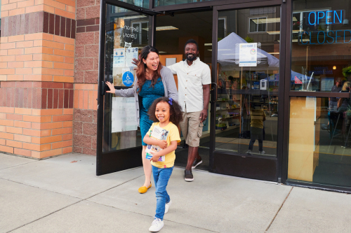 Hombre, mujer y niño salen por la puerta de la Biblioteca Betania