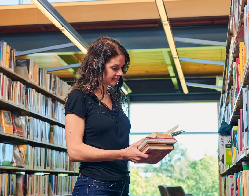 A woman looking at books in the library.