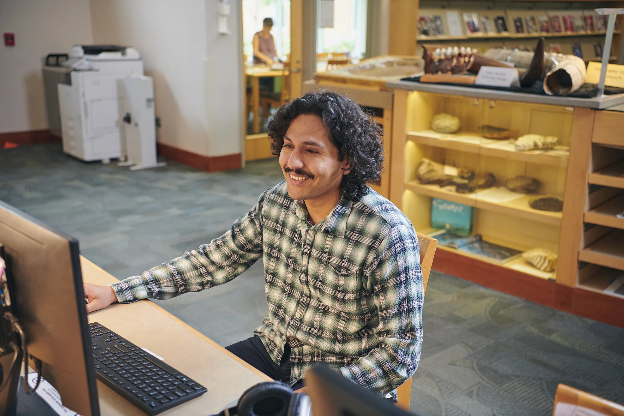 Person with dark hair and mustache uses a computer in the library