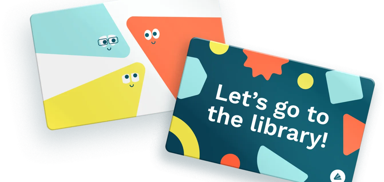 Two WCCLS student library cards. The card of the left has colorful triangles with smiling faces on them. The card to the right has a navy background with colorful shapes and words "Let's go to the library!".