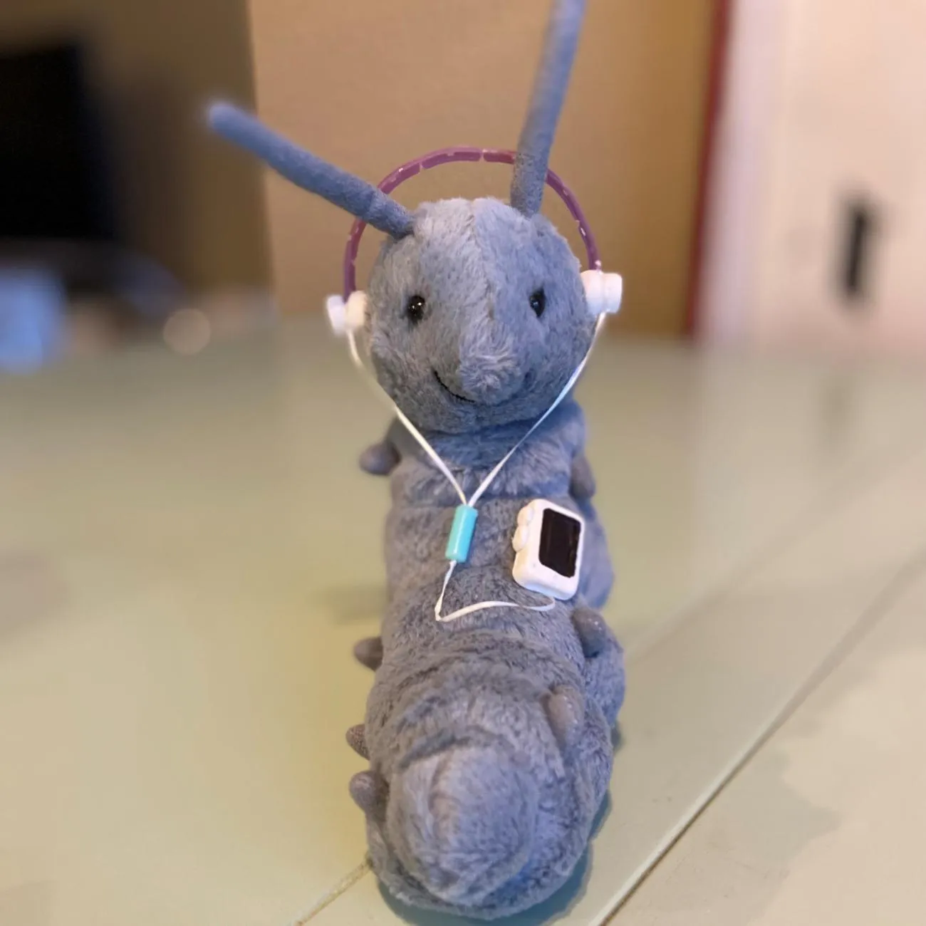photo of stuffed animal caterpillar wearing a pretend audio player