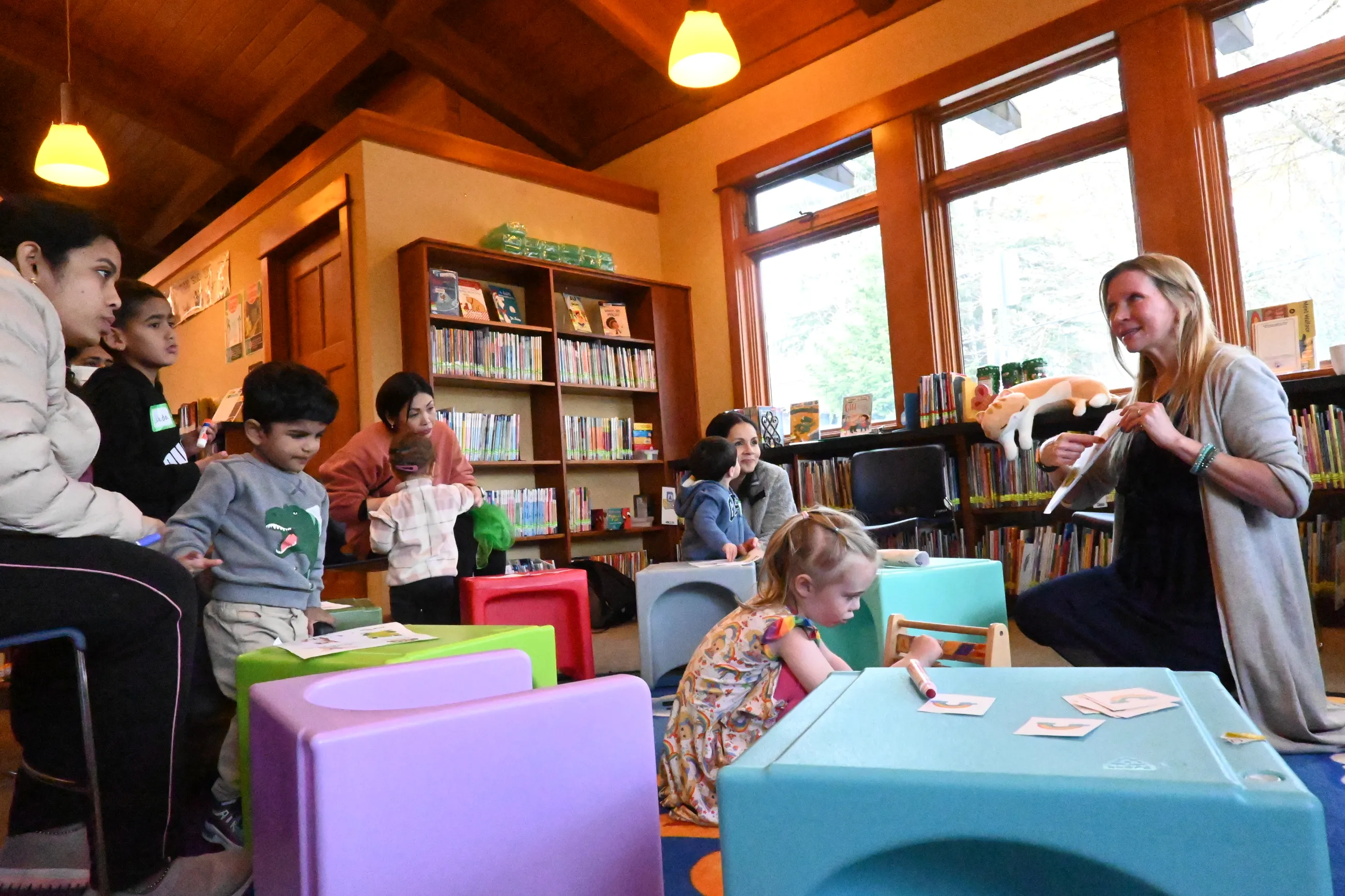 Group of children and their parents listening to library staff reading a book at storytime.