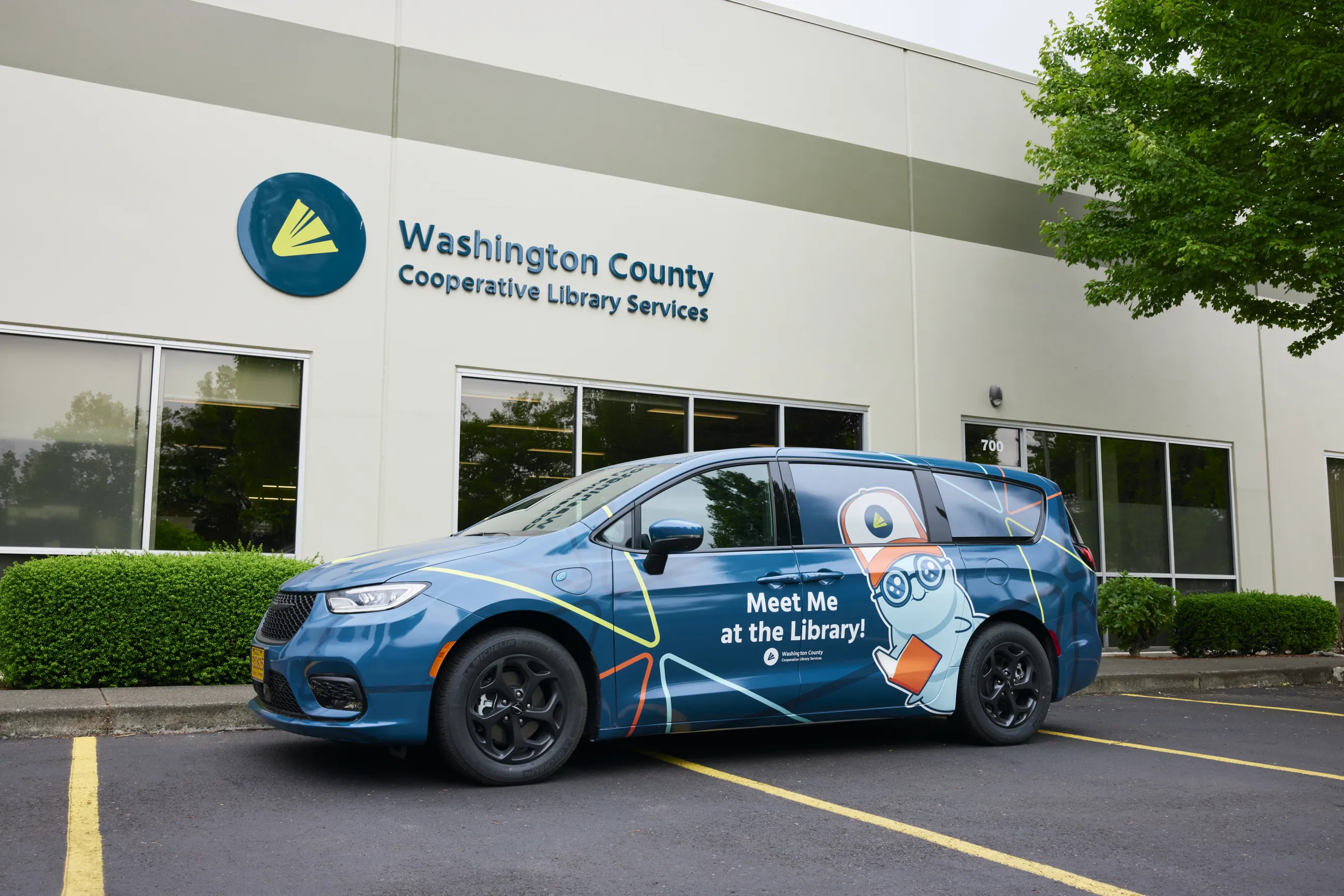 WCCLS partnerships van in front of office building with WCCLS logo signage.