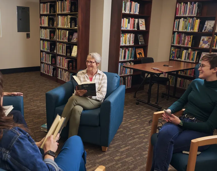 Book group meeting in the library, sitting in blue chairs.