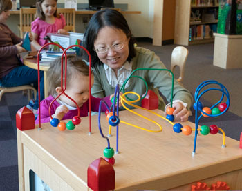 Woman and child playing with bead cubes