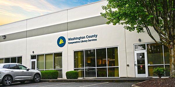 Vista exterior de las oficinas de administración de WCCLS, que muestra un edificio de color crema con grandes ventanales y un letrero de WCCLS.