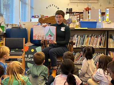 Bibliotecario lee un libro infantil a una clase de estudiantes de primaria