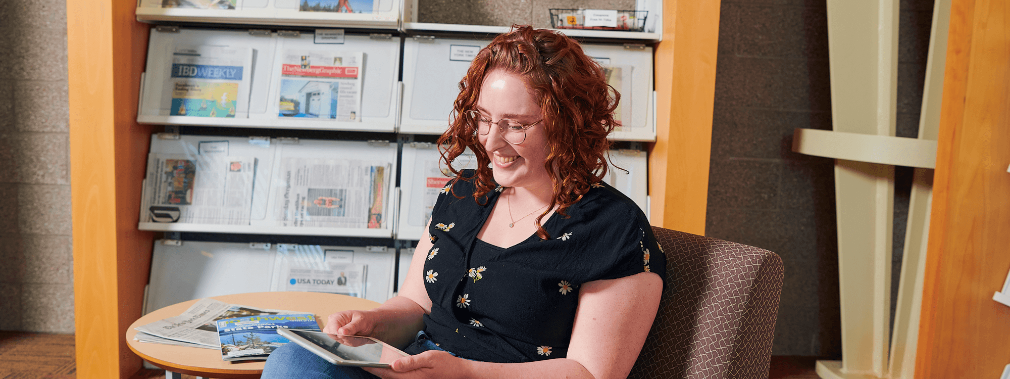 Smiling woman in chair looking at tablet on her knee