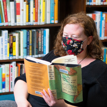 Woman reading a book in a chair at West Slope Library